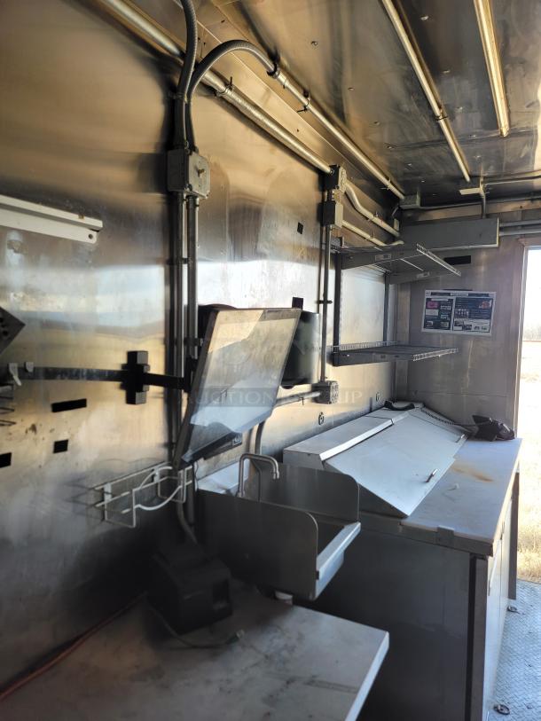 Commercial stainless steel food truck interior, featuring preparation area, sink, shelving, and electrical outlets. Good condition.