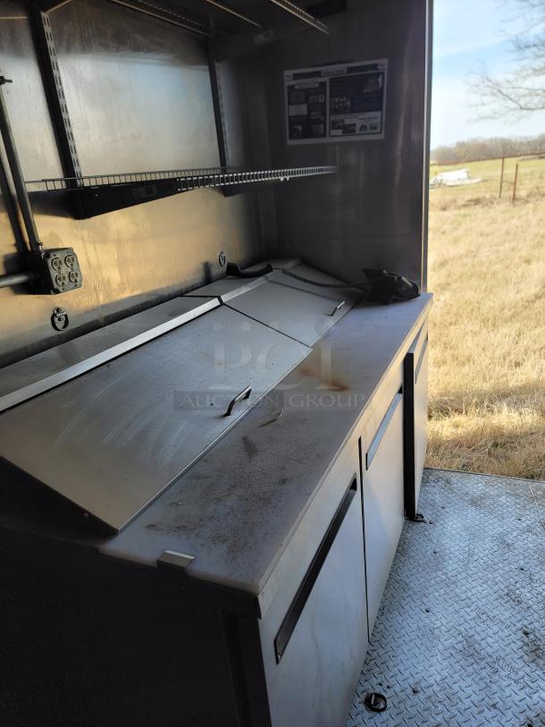Commercial stainless steel prep station with two compartments, wire shelf, and visible wear. Ideal for food service use.