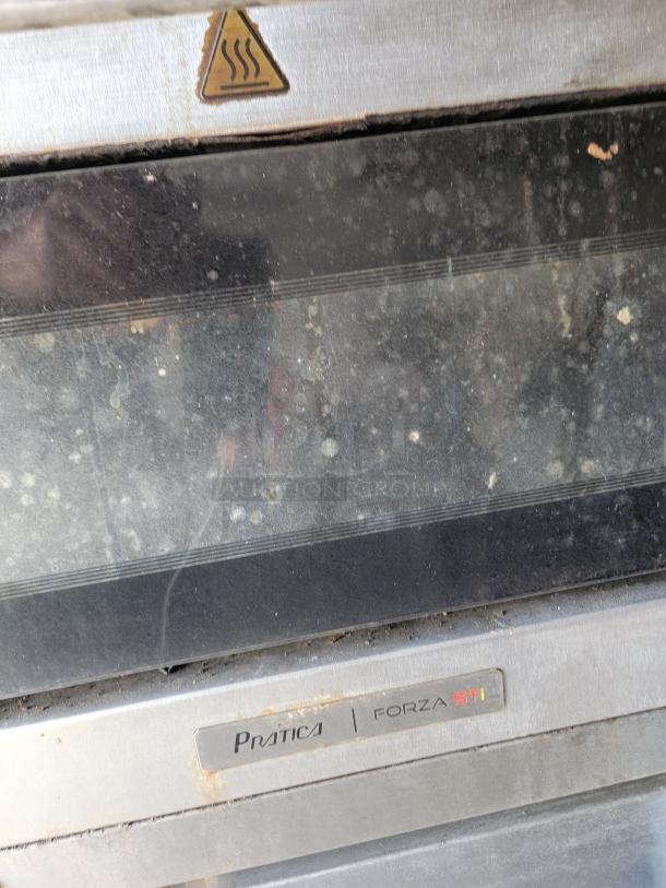 Pratica Forza STi oven with warning symbol, showing signs of wear. Stainless steel exterior and glass door.