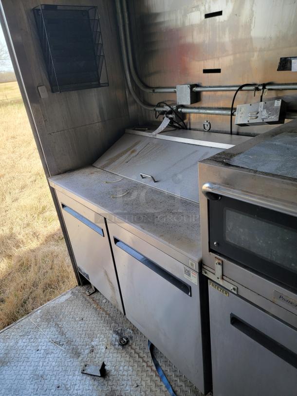 Industrial kitchen workstation with stainless steel cabinets, labeled "Freezer." Shows some wear and grime.