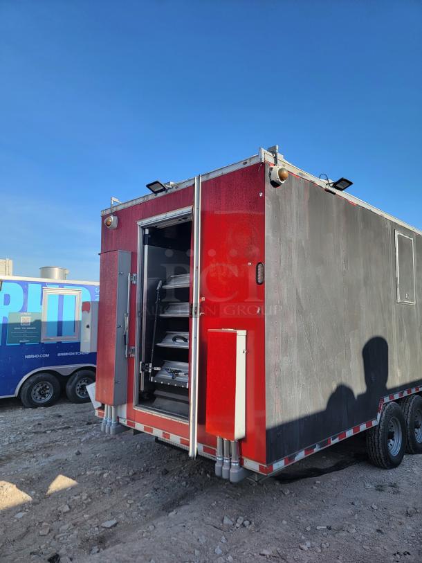 Red and black mobile trailer with open rear door revealing shelves inside, dual axles, and rooftop lights, suitable for various utility purposes.