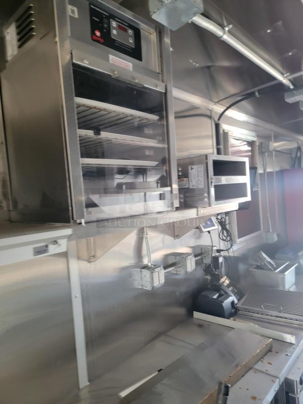 Commercial kitchen setup with stainless steel shelves, industrial equipment, and visible control panel in clean condition.