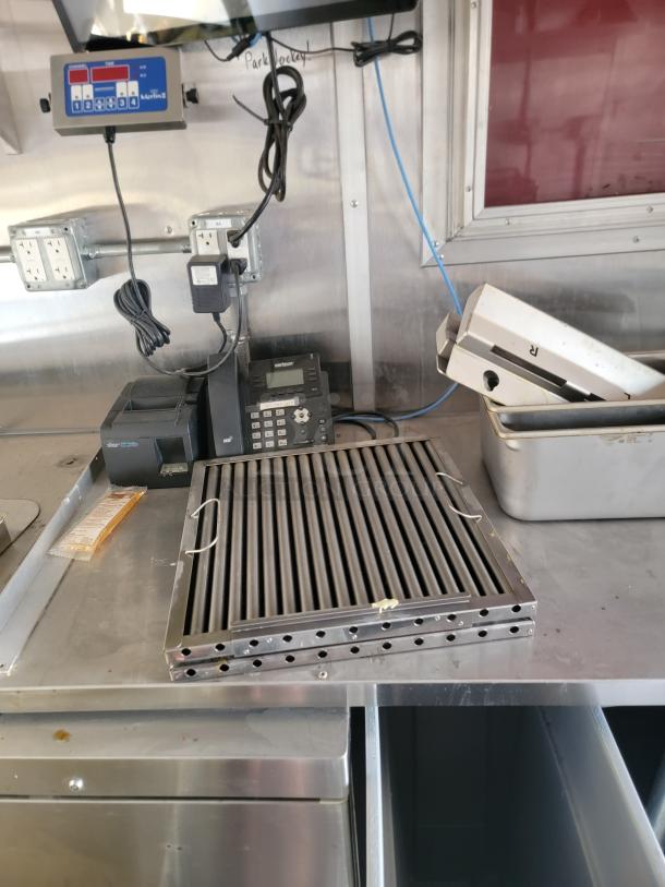 Stainless steel grill grate with vent holes, in excellent condition, on a metallic counter in a commercial setting.