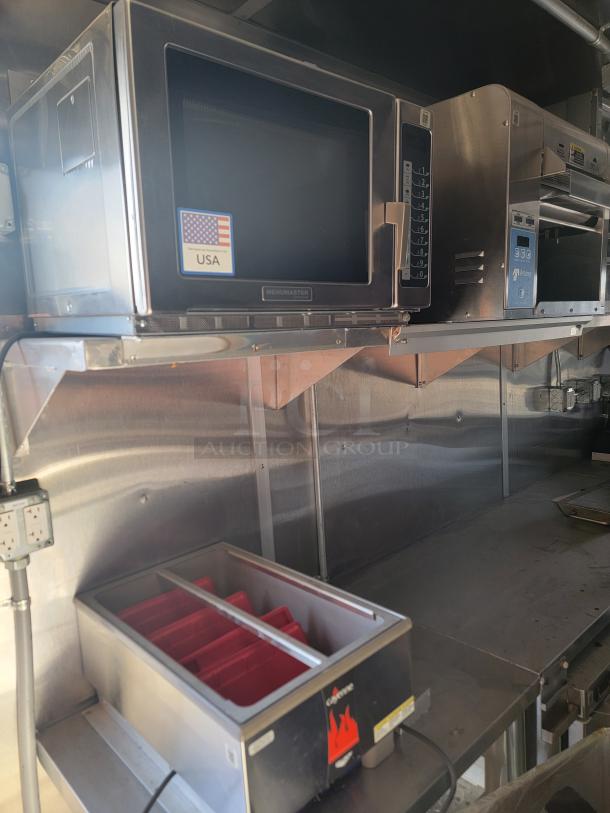 Menumasters microwave with keypad, stainless steel, American-made logo. Below, a heated food warmer with red bins, good condition.