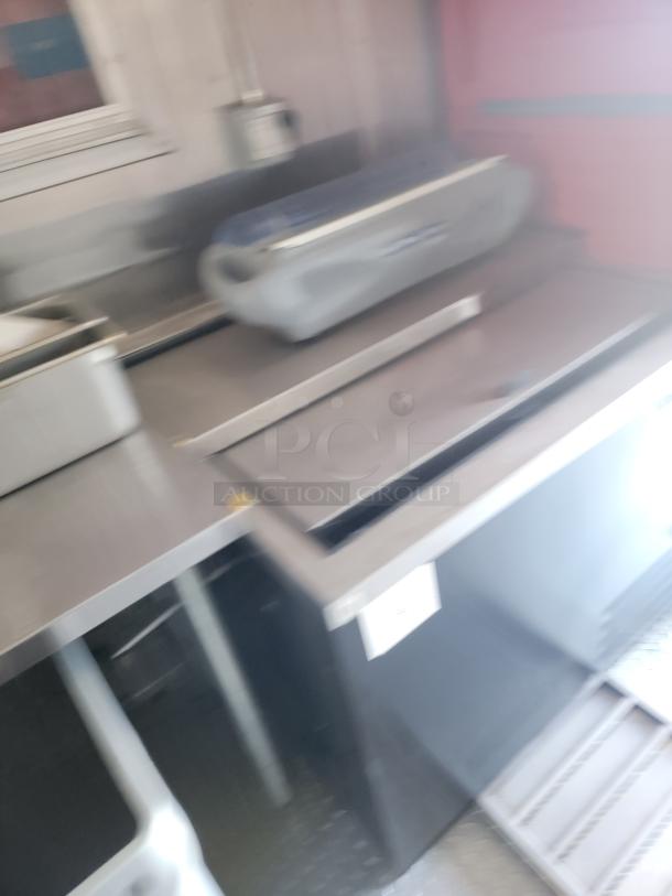Blurred image showing industrial kitchen equipment, stainless steel surfaces, and appliances.