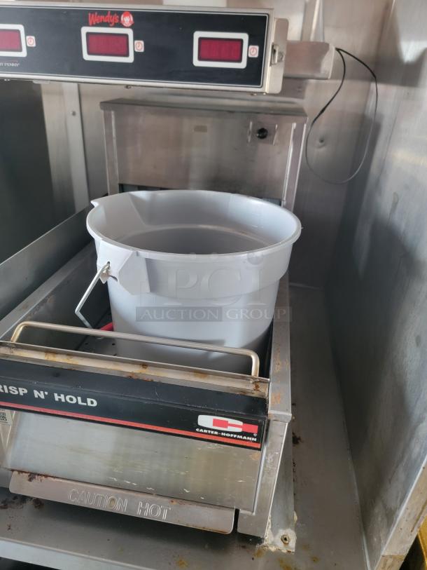 Carter-Hoffmann Crisp N' Hold unit with attached Wendy's panel. Features digital display and a plastic bucket. Shows wear and rust.