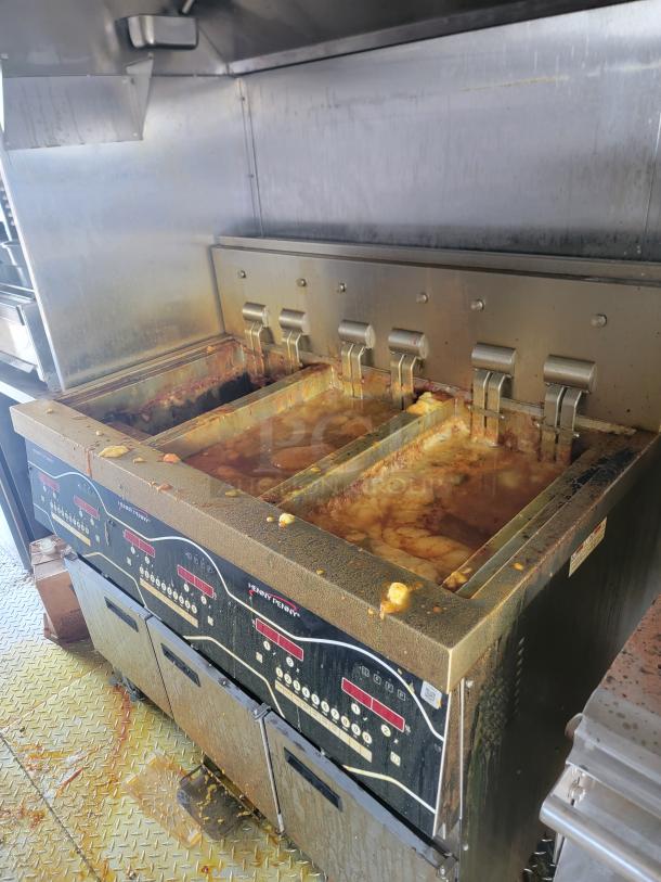 Henny Penny commercial deep fryer with multiple fry baskets, stainless steel construction, showing signs of heavy use.