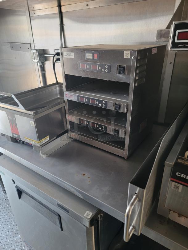 Commercial kitchen equipment with stainless steel casing, featuring multiple digital control panels and power switches, in used condition.