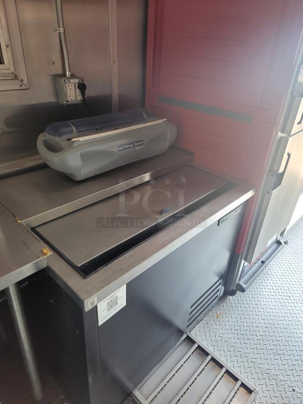Commercial refrigerated prep table with True TUC-27D-2 label. Saf-T-Wrap station on top. Minor wear visible.