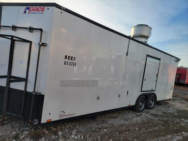 Pace American trailer with "REEF GS 8769" marking, in good condition. Features dual axles, rooftop equipment, and side door.