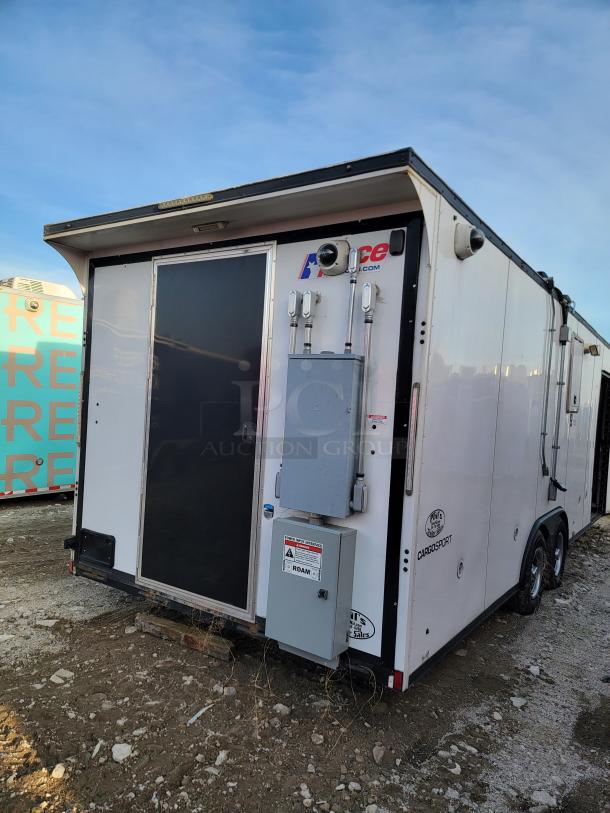 White cargo trailer with "Cargosport" and "Pace" logos. Features dual axles, side door, and external electrical panel. Good condition.