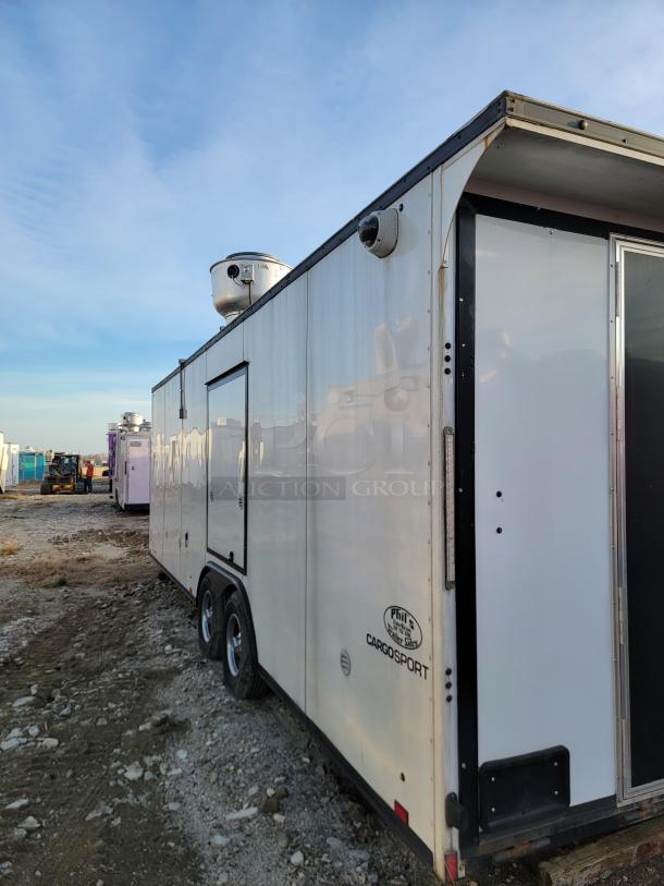 Enclosed cargo trailer, brand logo "CargoSport" visible. Features include dual axles, roof vents, and security cameras. Good condition.