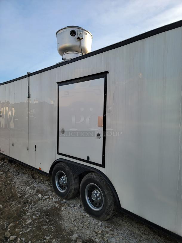Mobile concession trailer with dual axles and roof-mounted exhaust fan. Features exterior service panel. Appears in good condition.