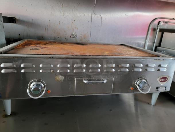 Commercial griddle by Wells in used condition, featuring dual control dials, metal exterior with rust spots, and visible brand logo.