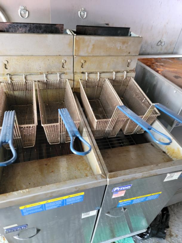Pitco commercial deep fryer with dual baskets, blue handles, stainless steel body, worn condition, safety labels visible.