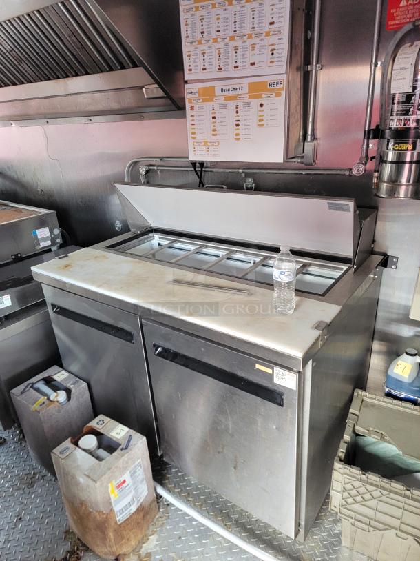 Commercial stainless steel prep table with refrigerated base, double doors, and condiment containers. Includes build chart above.