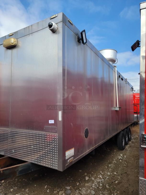 Stainless steel mobile trailer with surveillance cameras and lighting, triple axle, exterior vents, roof-mounted dish, minor wear.