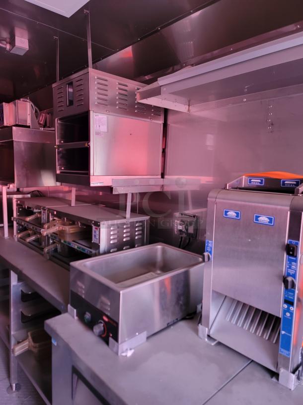 Commercial kitchen equipment includes stainless steel ovens, a warming drawer, and a conveyor toaster in excellent condition.