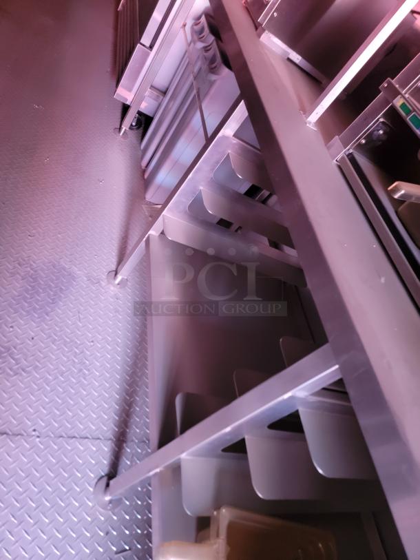 Metal storage rack with adjustable shelves, positioned on a textured floor. No visible labels or markings.
