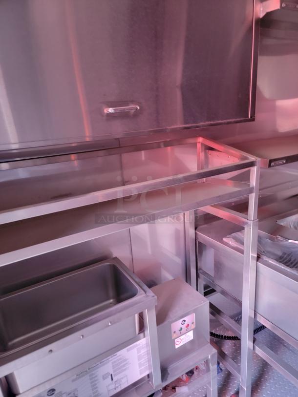 Stainless steel commercial kitchen equipment with sink, shelving, and heating unit. Good condition, ideal for food service.