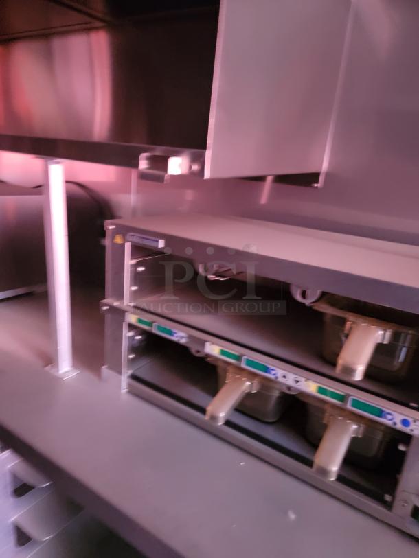 Commercial kitchen equipment featuring two grill units with metal handles and control panels, stainless steel finish, in good condition.