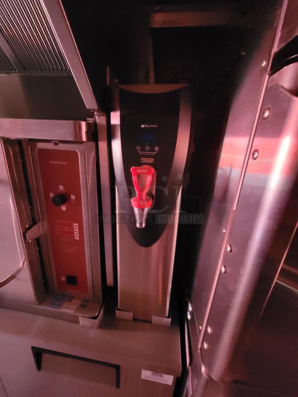 Bunn hot water dispenser with red spout. Stainless steel finish. Branded logo visible. Good condition.