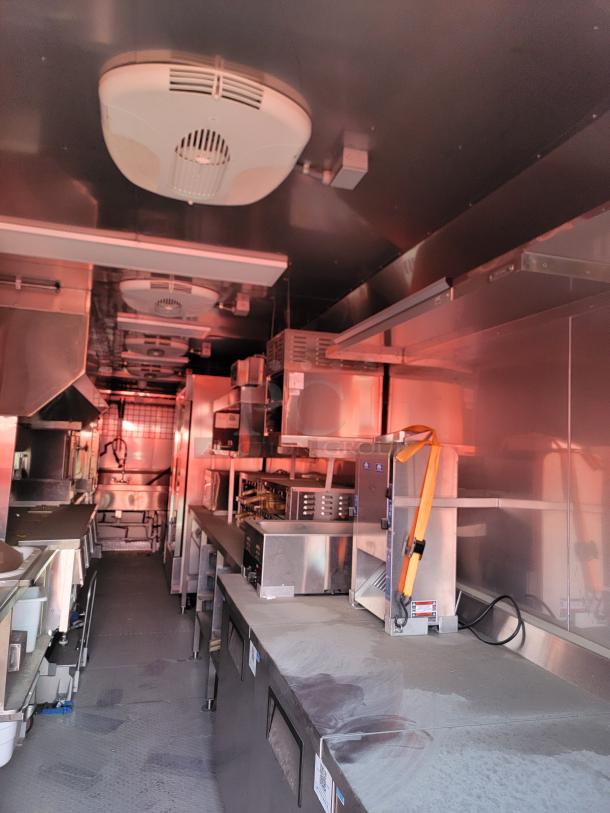 Commercial kitchen interior with stainless steel appliances, ventilation system, and shelving. Clean condition, ready for use.