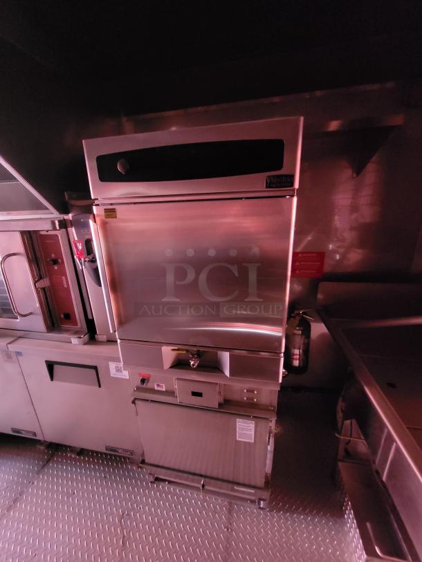 Commercial kitchen appliance, stainless steel, with visible labels. Features oven and storage compartments. Excellent condition.
