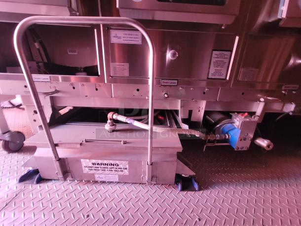 Industrial metal equipment with pipes and levers, labels for drain levers visible, warning for fire hazard. Used condition.