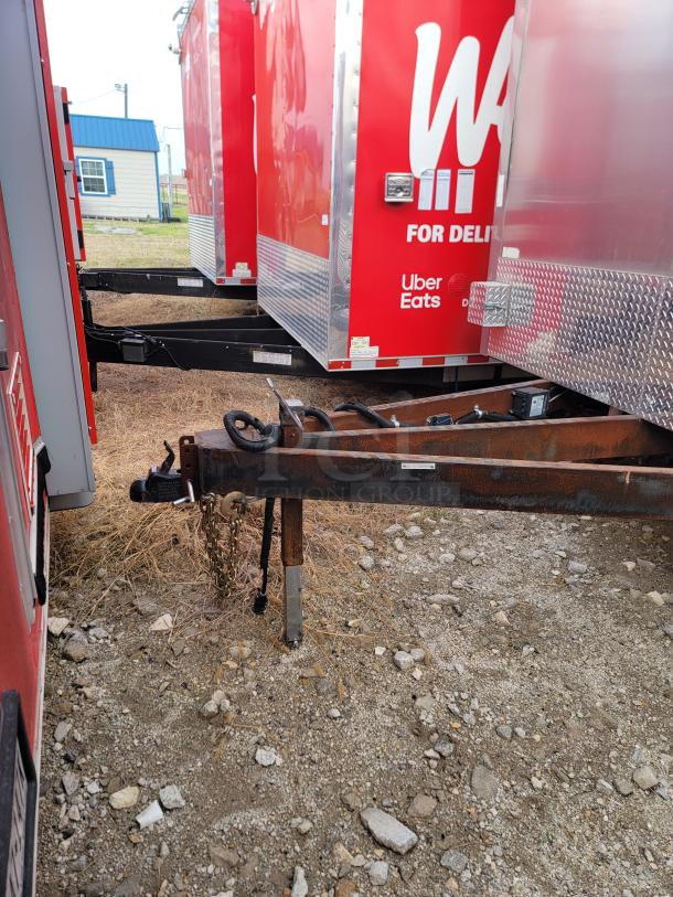 Red delivery trailer with Uber Eats branding, showing rusted hitch and stabilizer. Diamond plating on lower section.