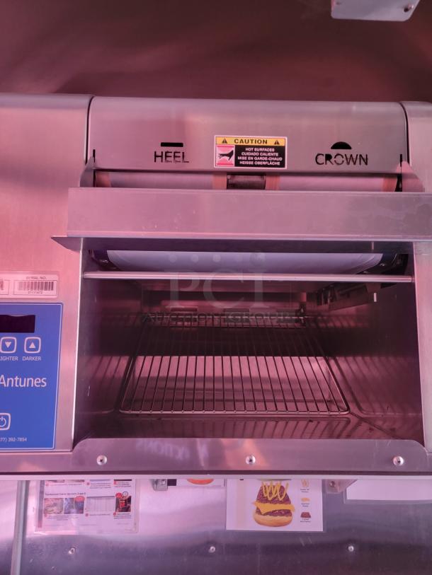 Commercial toaster oven by Antunes, labeled with "Heel" and "Crown." Visible caution sign about hot surfaces. Good condition.