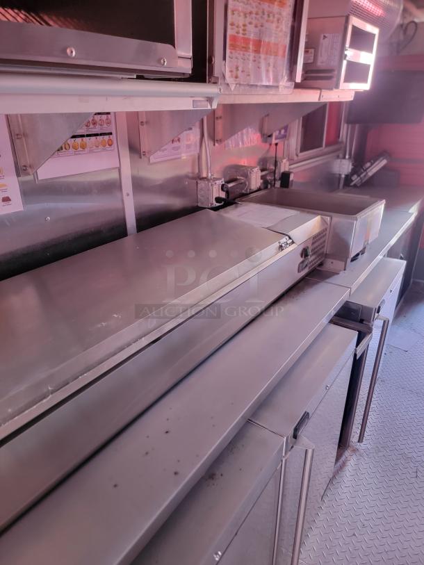 Commercial kitchen equipment with stainless steel surfaces, featuring multiple shelving units and storage compartments. Visible menus suggest use in a food service environment. Good condition.