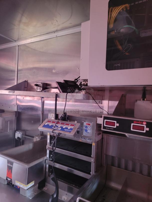 Commercial kitchen equipment with digital controls, stainless steel finish, APC network cabinet, and Wendy's timer. Good condition.