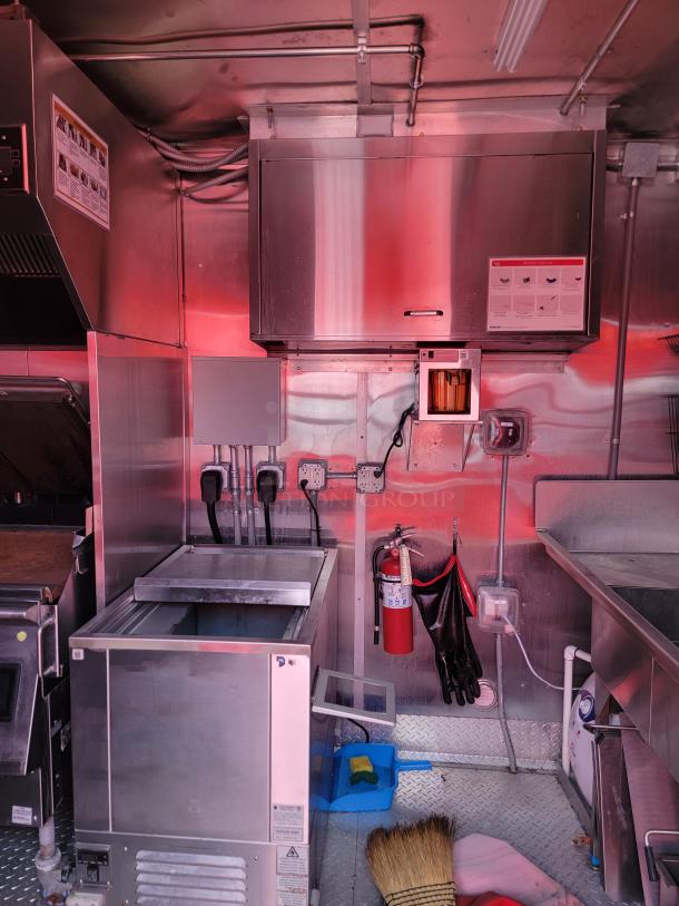 Commercial kitchen interior with stainless steel appliances, including a freezer, sink, and fire extinguisher. Clean and well-maintained.