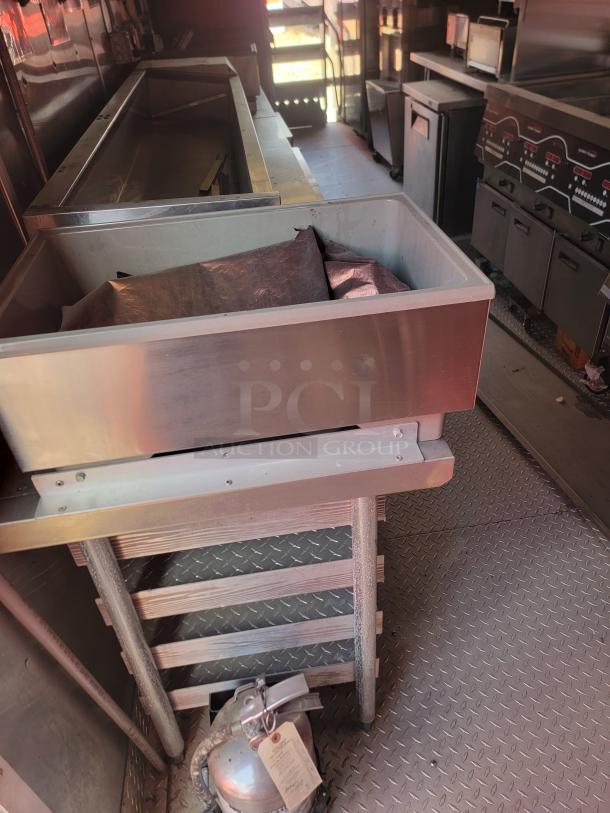 Commercial kitchen setup with stainless steel counters and fryers. Includes a silver fire extinguisher with a visible tag.