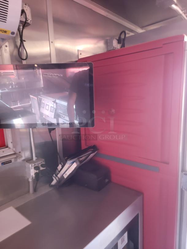 Red commercial equipment cabinet with vented door in stainless steel interior. Attached flat screen monitor displaying kitchen setup.