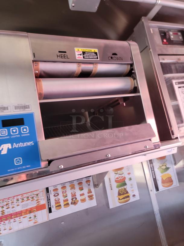 Antunes commercial toaster with "Heel" and "Crown" rollers, stainless steel, caution label visible, build card guides below.