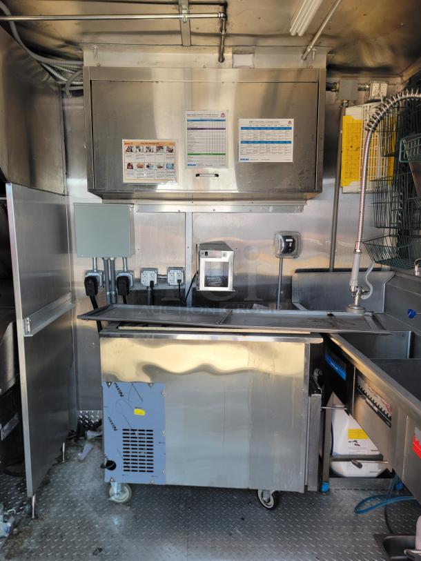 Commercial stainless steel kitchen equipment with refrigeration unit on wheels, mounted control box, and utility sink. Labels indicate power usage.