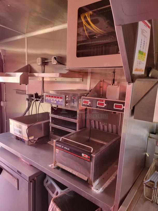 Commercial kitchen equipment setup, featuring a Crisp N' Hold warming station and various electrical components. Good condition.