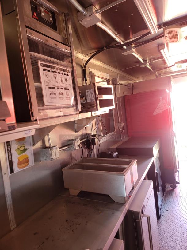 Commercial kitchen interior with stainless steel equipment. Features heating unit with control panel and storage areas. Clean condition.