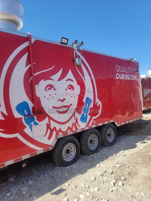 Red food truck with a Wendy's logo, featuring "Quality is our Recipe" text, triple axle, in outdoor setting.