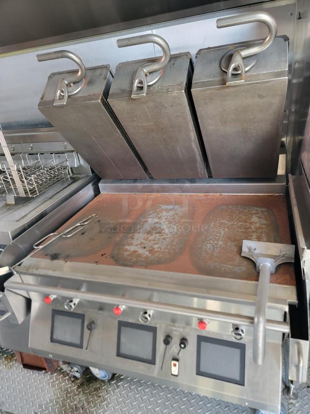 Commercial griddle with four vertical heating elements, control panel, and grease scraper. Shows signs of wear.
