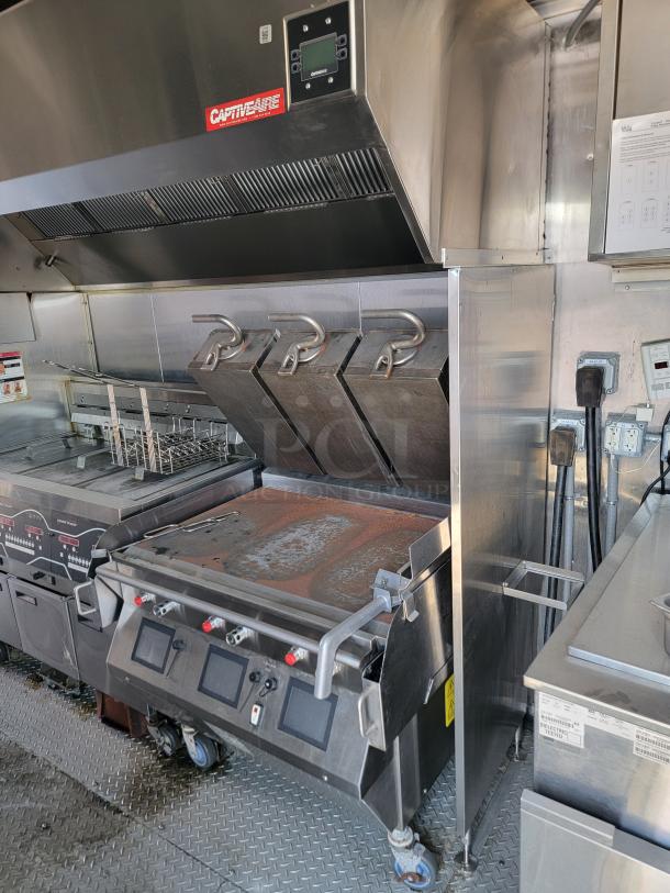 Commercial kitchen equipment with CaptiveAire hood, grills, and fryers. Stainless steel finish, used condition.