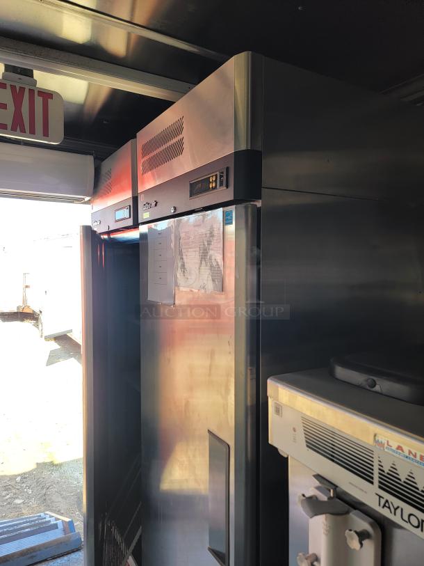 Commercial stainless steel refrigerator, digital display, good condition, located indoors. Exterior shows exit sign above.