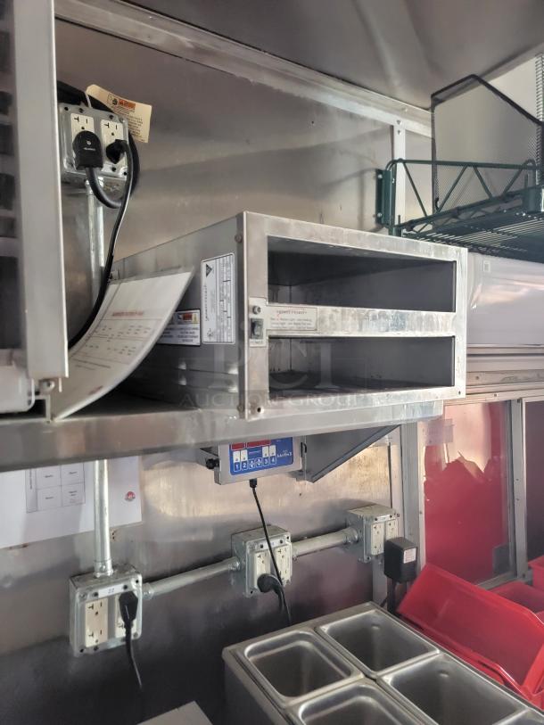Stainless steel food warming drawer with control panel, mounted on a wall. Used condition with visible wiring and labels.