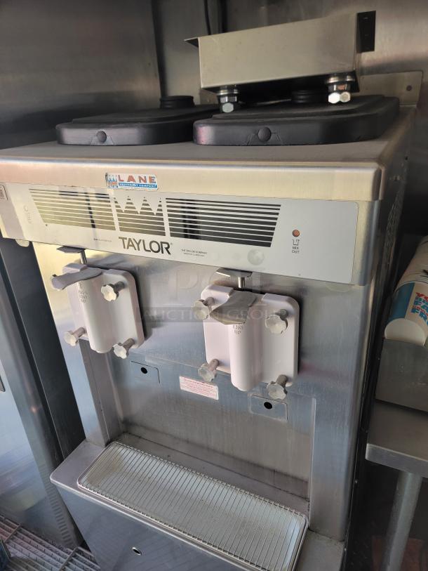 Taylor commercial soft serve machine with dual dispensers, metal finish, visible Lane Equipment Company label, good condition.
