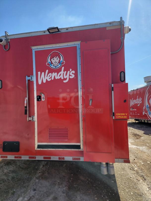 Red Wendy's mobile food trailer with side door, prominent logo, and visible 120/208V 3 Phase electrical marking.