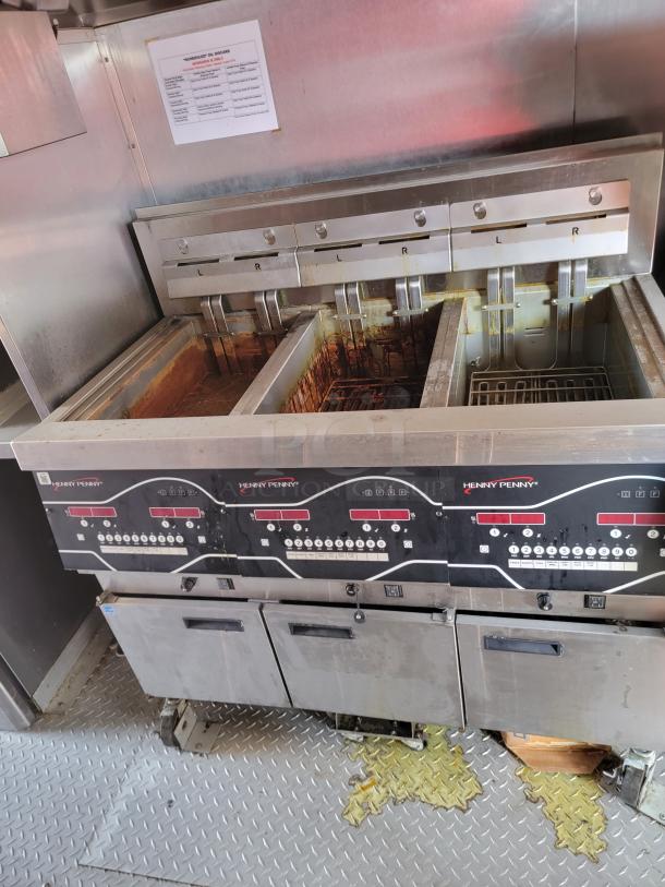 Henny Penny commercial fryer with four fry wells, stainless steel, digital controls, visibly used condition.
