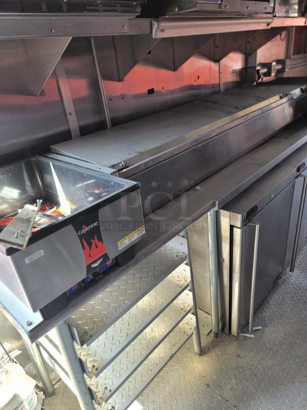 Commercial kitchen setup featuring a Cayenne countertop warmer and stainless steel surfaces, showing moderate wear.