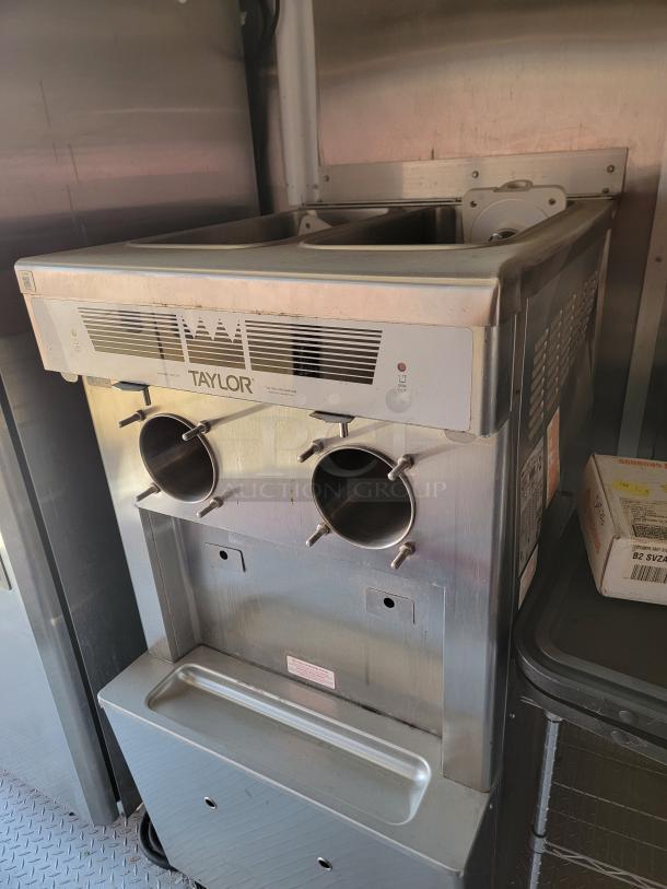 Taylor ice cream machine with dual dispensers, stainless steel, used condition. Model numbers and labels visible indicate maintenance details.